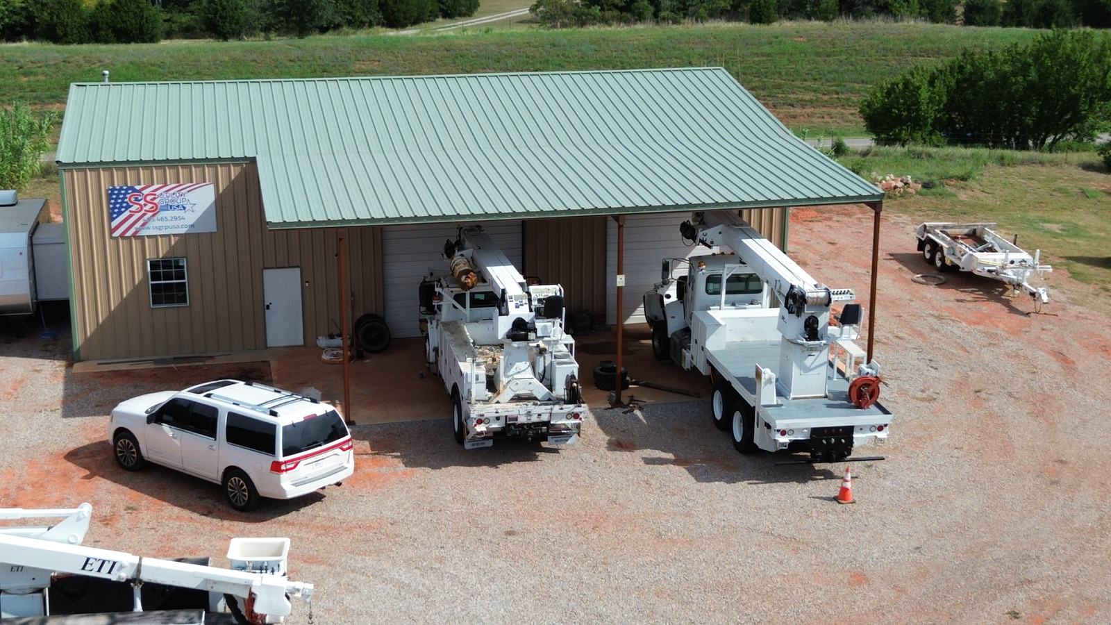 SS Utility Group yard in Jones, Oklahoma, with bucket trucks and digger derricks under the covered bay